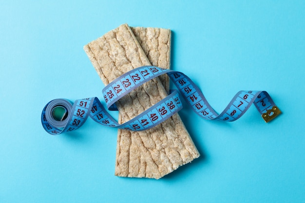 Ruban à mesurer et pain diététique sur fond bleu