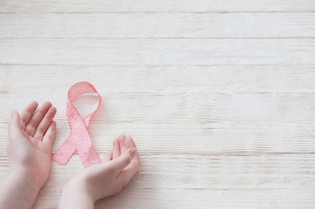 Ruban rose à la main comme symbole de lutte contre le cancer du sein