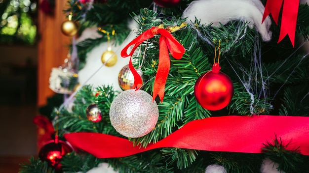 Ruban rouge avec des boules de Noël rouges et des boules d'argent ornent le fond de Noël du sapin de Noël