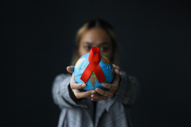 Ruban rouge et globe du sida dans les mains des femmes pour la Journée mondiale de lutte contre le sida