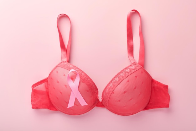 Ruban de sensibilisation au cancer du sein Soutien-gorge rouge et ruban rose allongé sur le soutien-gorge féminin sur fond Sensibilisation au cancer du sein et octobre Journée rose Journée mondiale du cancer Vue de dessus Maquette