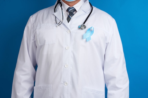 Ruban de soie bleu attaché à une blouse blanche d'un médecin. Sensibilisation au cancer de la prostate
