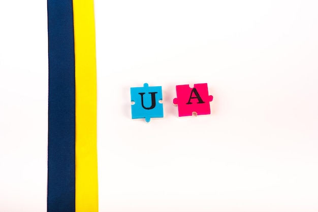 Ruban de tissu bleu jaune coloré et puzzles de lettres Ukraine isolé sur blanc Le symbole de l'état