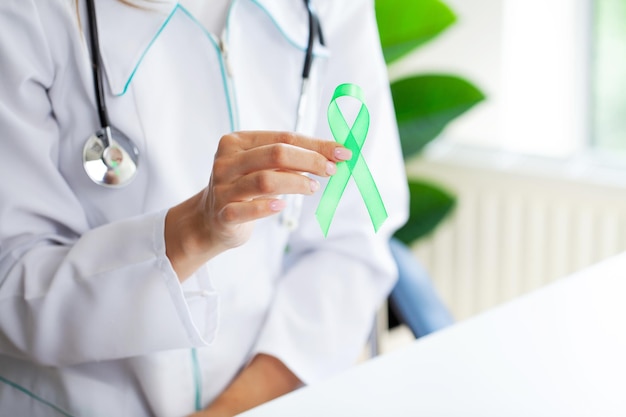 Ruban vert à la main comme symbole de sensibilisation au cancer du lymphome