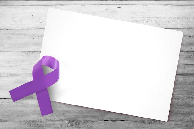 Rubans violets avec du papier blanc vierge sur fond en bois. Concept de la journée mondiale du cancer. Papier blanc vierge pour l'espace de copie