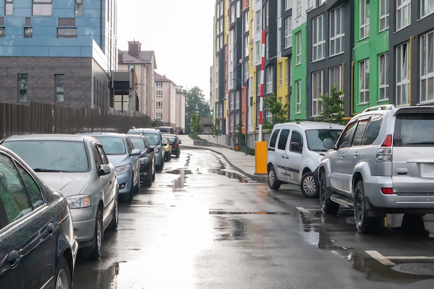 Rue dans une ville sans personnes avec des voitures garées par temps de pluie. Pluie sur la route. Pluie et voitures. Arrière-plan de voitures garées dans une rue pluvieuse de la ville. Voitures garées symétriques.