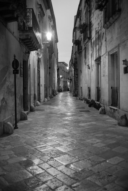 Une rue étroite entre les bâtiments la nuit.