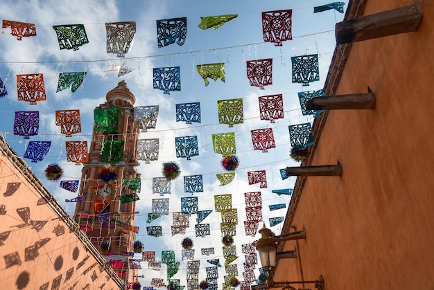 Une rue mexicaine avec des décorations colorées de Papel Picado et une église en arrière-plan