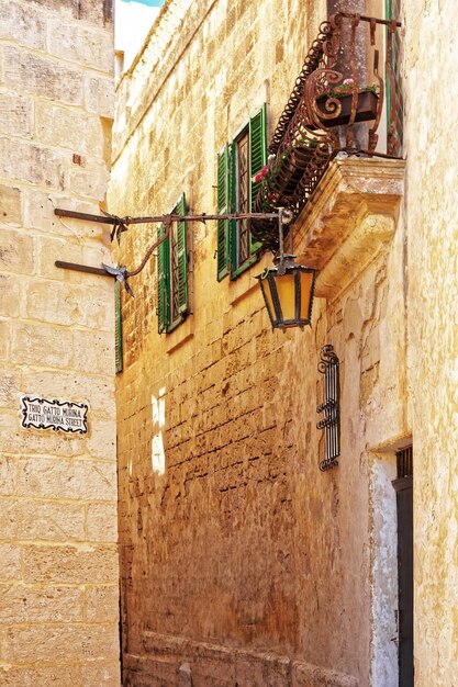 Rue silencieuse étroite avec lampe et balcon à Mdina, Malte