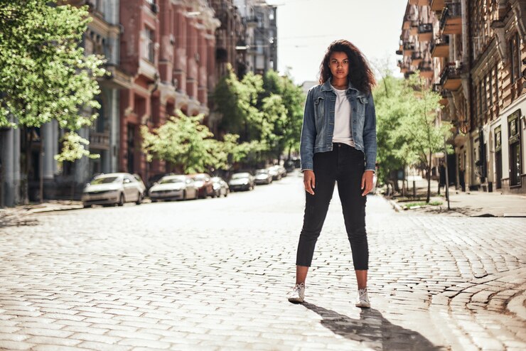 Photo rues vides jeune femme afro-américaine en vêtements décontractés, debout sur la route et regardant