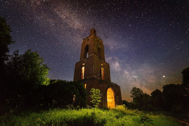 Ruine du clocher de nuit dans la forêt la nuit étoilée avec lumière interne