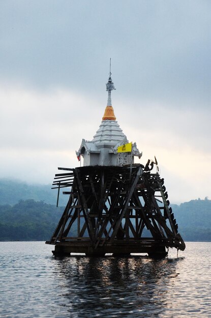 Photo les ruines antiques antiques ubosot de wat sri suwan se noient profondément sous l'eau de la rivière songkalia au coucher du soleil à l'aube pour les thaïlandais et les voyageurs étrangers visitent sangkhla buri à kanchanaburi en thaïlande