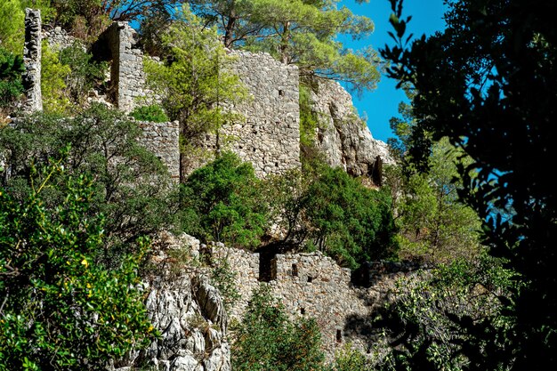 Ruines des murs antiques de forteresse sur des pentes boisées de montagne dans la ville antique d'Olympos, Turquie