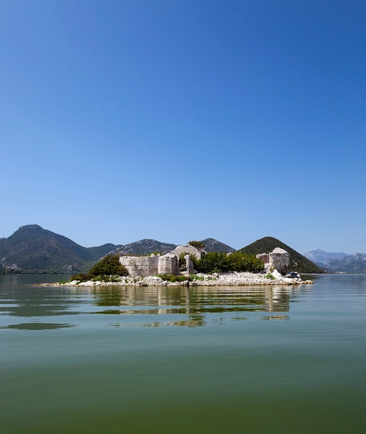 Les Ruines D'une Prison Sur Une île Du Lac De Skadar. En Arrière-plan Sont Placées Des Montagnes. Monténégro.