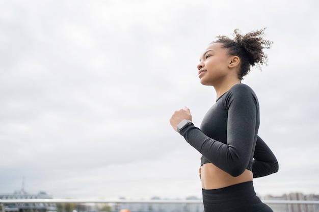 Runner woman utilise un tracker sur sa montre intelligente pour l'entraînement sportif dans les vêtements de sport