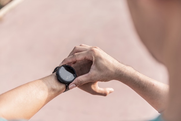 Photo running man à la recherche d'une montre de sport. homme jogging en utilisant une montre intelligente à l'extérieur