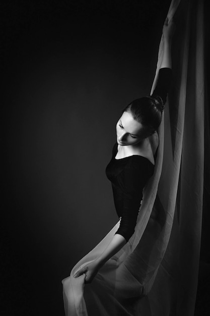 Russie, Moscou, 1er octobre 2017 : Gymnaste féminine posant sur fond noir et tissu blanc. Photo d'art d'une gymnaste. photo en noir et blanc