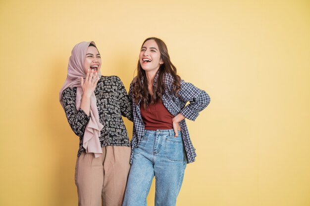 S'amuser de deux belles femmes qui rient en discutant et en s'embrassant les mains sur les épaules avec...