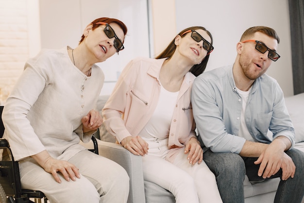 S'amuser. Encourager les handicapés. Mère en fauteuil roulant et enfants adultes regardent un film en 3D.