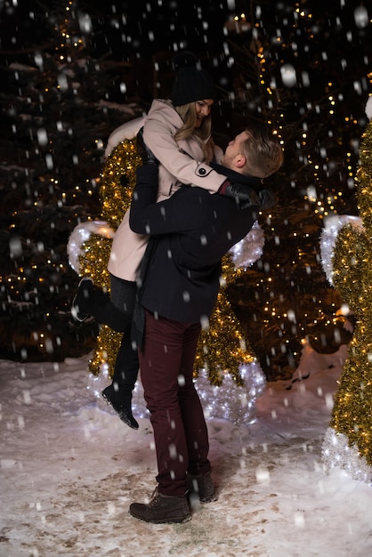 S'amuser ensemble à une fée de Noël Jeune couple joyeux se promène en s'habillant chaudement en se regardant et en riant