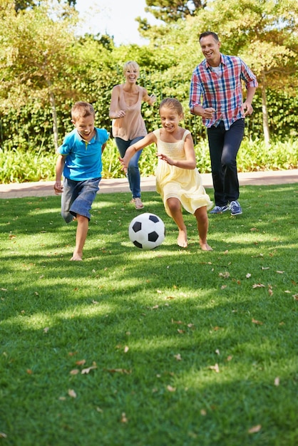 S'amuser en famille au parc Une famille heureuse jouant au football dans le parc par une belle journée d'été