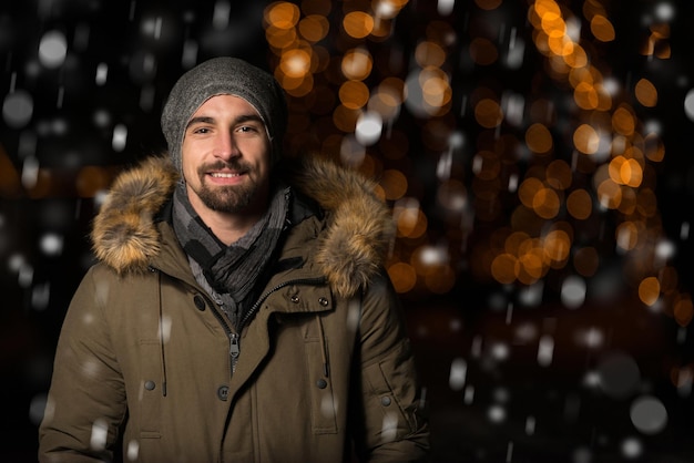 S'amuser à une fée de Noël Un jeune homme gai vêtu de chaud est debout dans un marché de vacances