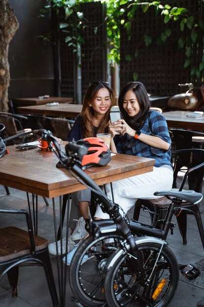 S'amuser femme asiatique appréciant discuter et utiliser un smartphone lors d'une pause au café