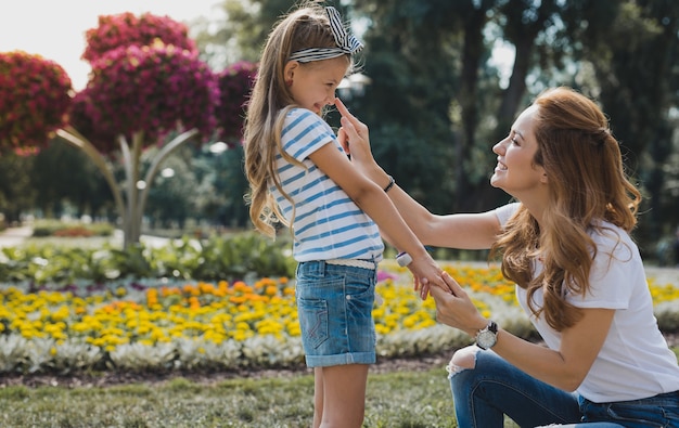 S'amuser. Joyeuse mère à la mode se sentir bien tout en s'amusant avec sa jolie fille dans le parc