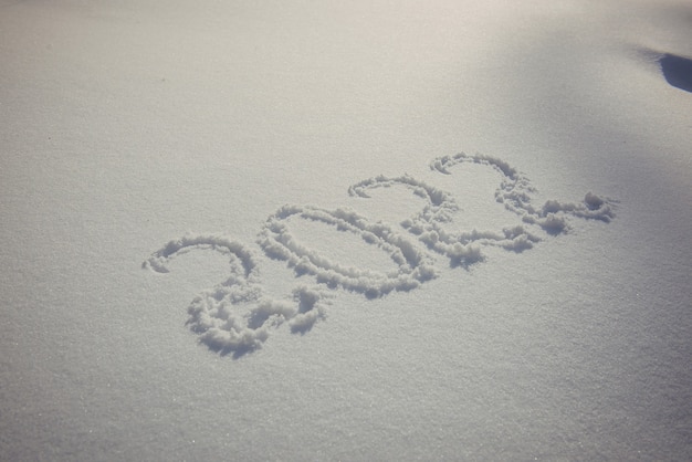 S'appuyant sur la neige blanche au soleil. Date du nouvel an, chiffres 2022, gros plan.