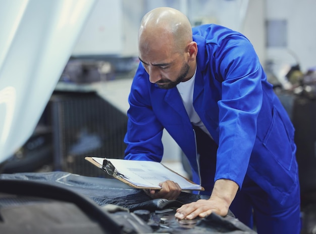 S'assurer que tout est aux normes. Photo recadrée d'un beau jeune mécanicien masculin travaillant sur le moteur d'une voiture pendant un service.