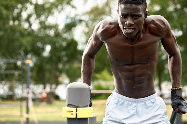 S'entraîner le matin Jeune homme africain fort en vêtements de sport faisant de l'exercice à l'extérieur Concept d'entraînement sportif Mode de vie actif sain TRX