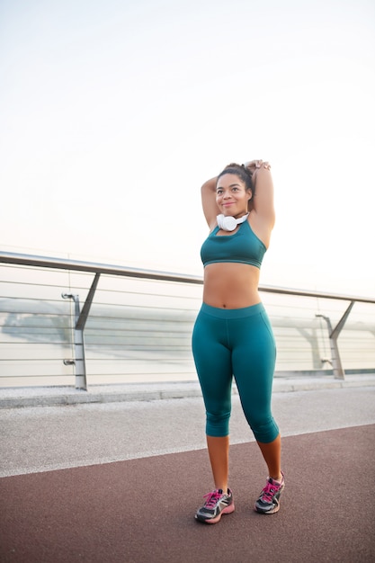 S'étirer avant de courir. Femme à la peau sombre portant des leggings et des étirements avant de courir