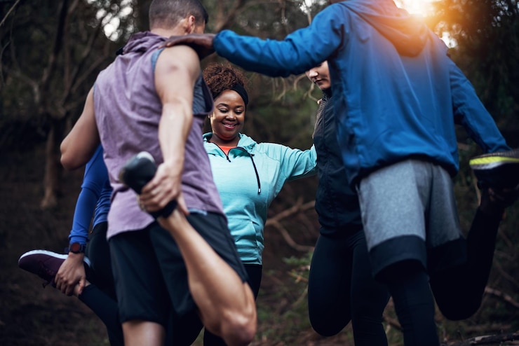 Photo s'étirer ensemble et s'entraider photo recadrée d'un jeune groupe d'amis sportifs travaillant dans la forêt