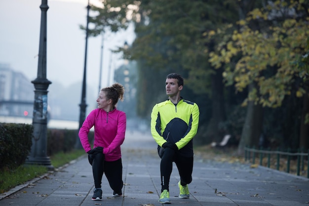 s jeune couple de jogging s'échauffant et s'étirant avant de courir le matin dans la ville