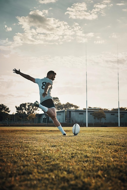 Photo sa technique est inégalée photo pleine longueur d'un beau jeune joueur de rugby qui frappe un ballon sur le terrain pendant la journée