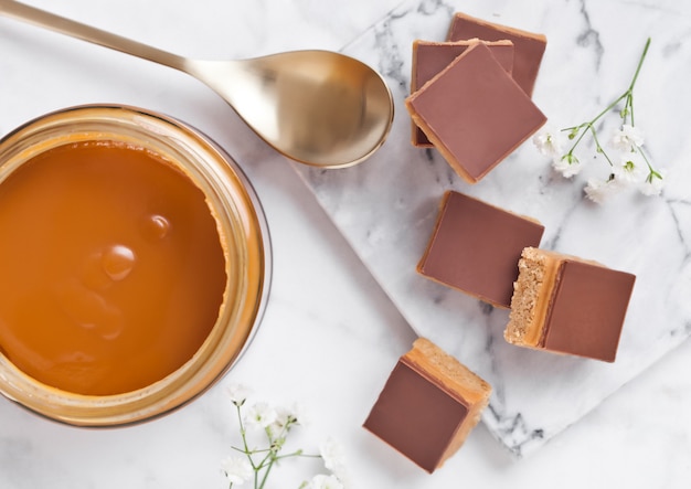 Sablé au caramel et biscuit mord le dessert sur une planche en marbre avec un pot de caramel salé et une cuillère dorée