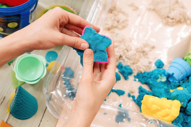 Sable cinétique. les mains des enfants jouent avec du sable polymère multicolore.