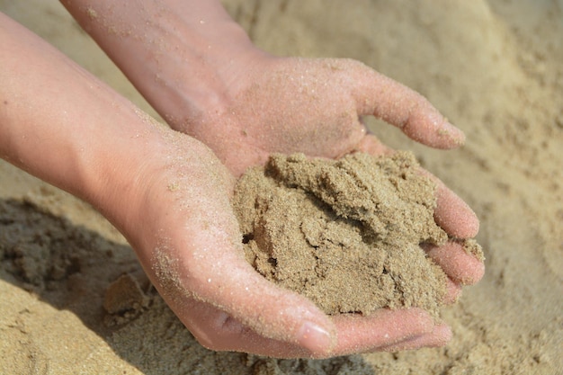 Sable dans les paumes des enfants Sur la plage