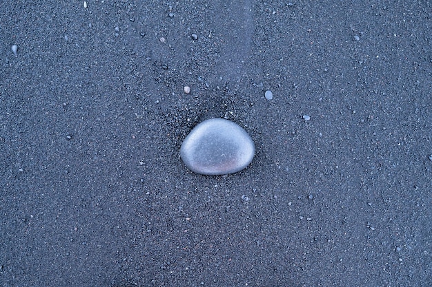 Sable noir et galets en arrière-plan Pierres rondes sur la plage Photographie pour le design Textures dans la nature
