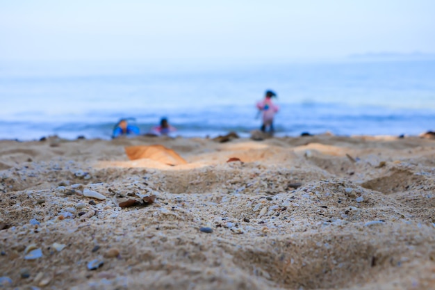 Sable à la plage avec fond de mer et les enfants floue