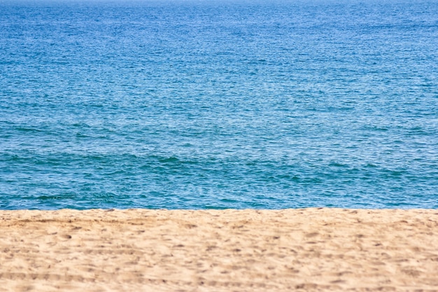 Sable sur la plage avec une mer bleue en arrière-plan, chaude journée d'été