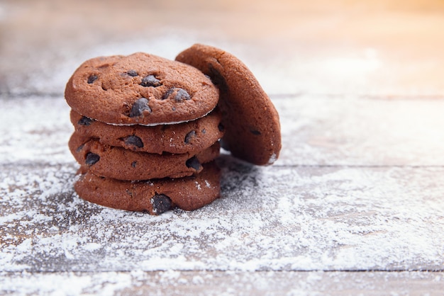 Sablés aux pépites de chocolat sur du bois saupoudré de sucre en poudre. Pâtisserie fraîche. Biscuits à l'avoine pour le dessert.