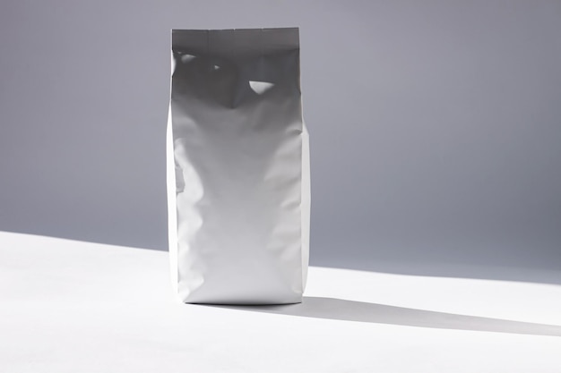 Sac en aluminium blanc vierge sur fond monochrome dans un style minimal avec une ombre de lumière naturelle Emballage pour aliments ou boissons