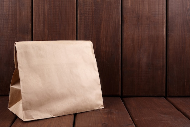 Sac d'artisanat cadeau marron sur fond en bois avec espace de copie. Cadeau surprise, livraison, concept de shopping