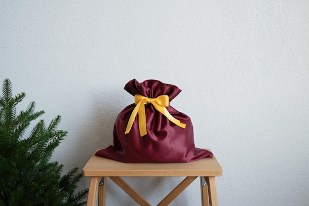 Un sac cadeau se dresse sur un escabeau près de l'arbre de Noël