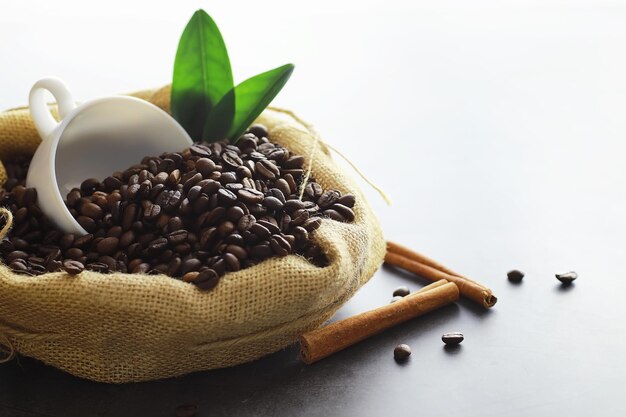 Sac de café. Grains de café torréfiés sur la table. Grains de café aux feuilles vertes pour la cuisson.