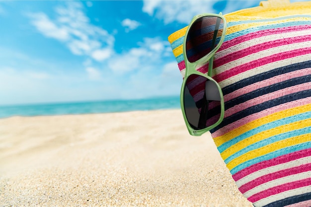 Sac coloré et lunettes de soleil sur la plage d'été