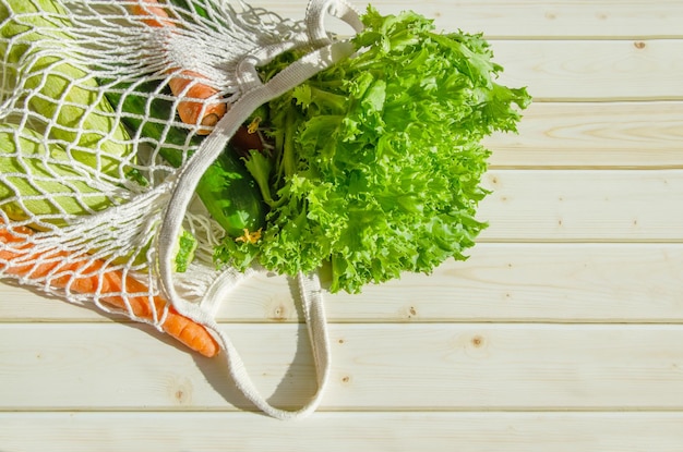 Sac à cordes avec des légumes frais Légumes frais de la ferme dans un sac en filet sur fond de bois rustique