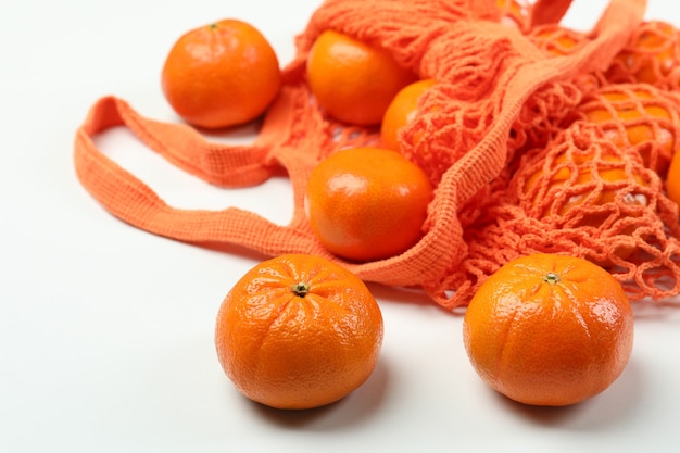 Sac à cordes avec des mandarines sur fond blanc