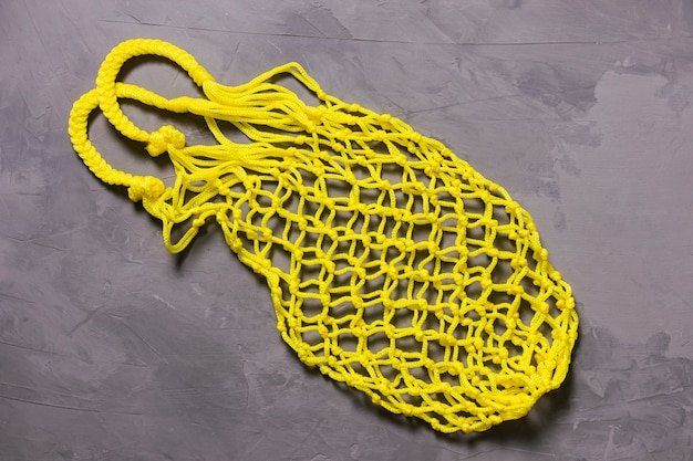 Sac à cordon jaune sur fond gris. Durabilité, zéro déchet, concept sans plastique, végétarisme, alimentation saine. Vue de dessus.